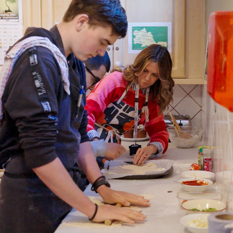 A student at a Glasshouse College residential home rolls out dough for baking bread.