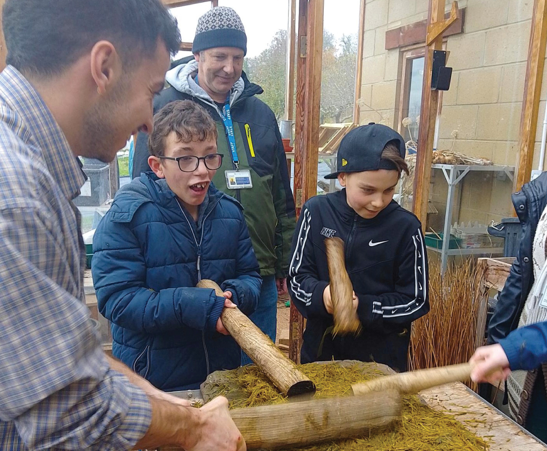 Pictured are staff and students hitting the wet hay as a step in the process of papermaking.