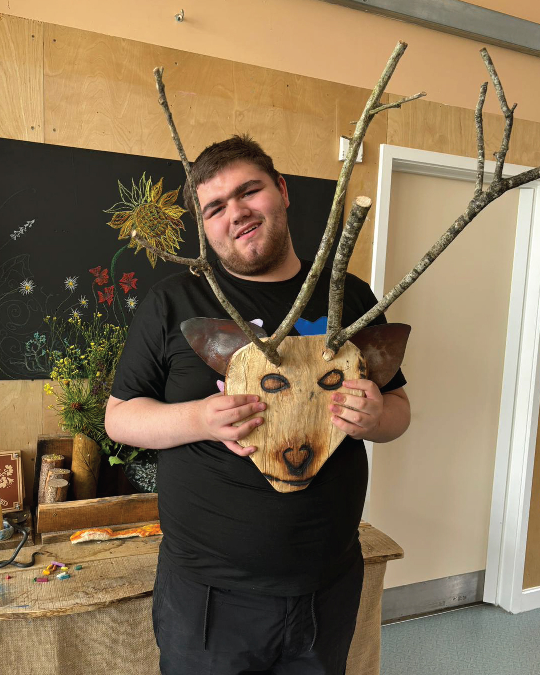 Sunfield student Jayden is stood showing the crafted stag’s head coat rack he created.