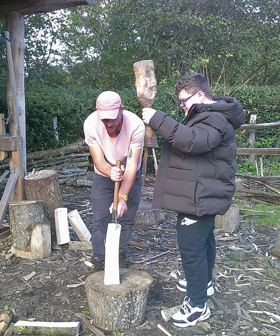 One of the students are pictured working in Green Wood Working. They are splitting wood with a member of staff 