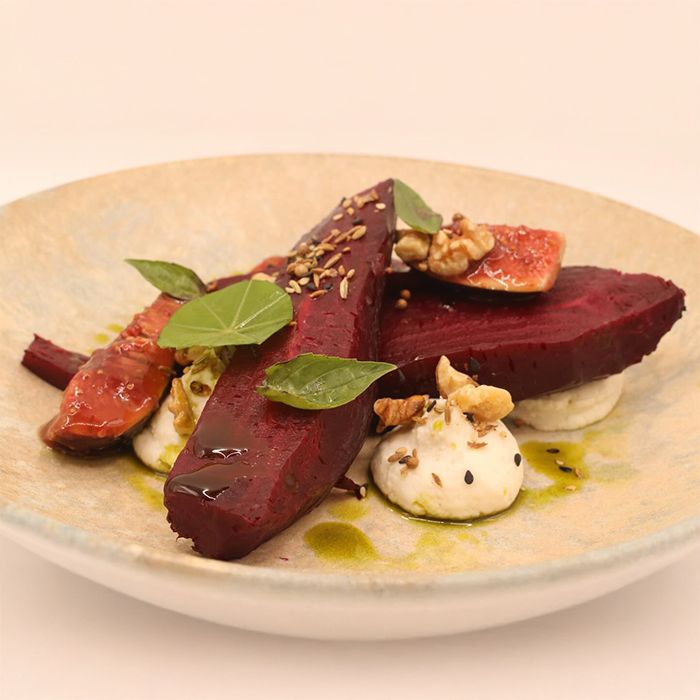 Pictured is a meal created by The Hive, dished on a beige plate the red colour of the beetroot pops. With a very light whipped goat’s cheese mixed with ricotta and aromatic cream. Fresh figs are then simply pickled in a cumin and anise vinegar/sugar solution. Walnut dukka is used for texture and balance. Basil oil, Pedro Ximénez vinegar and smoked salt for garnish. Rooftop nasturtium and cinnamon basil for freshness and colour.