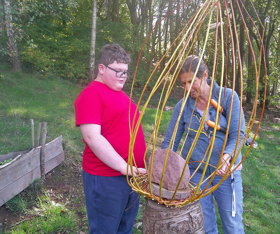 One student is pictured here with the willow sculpture with a staff member.