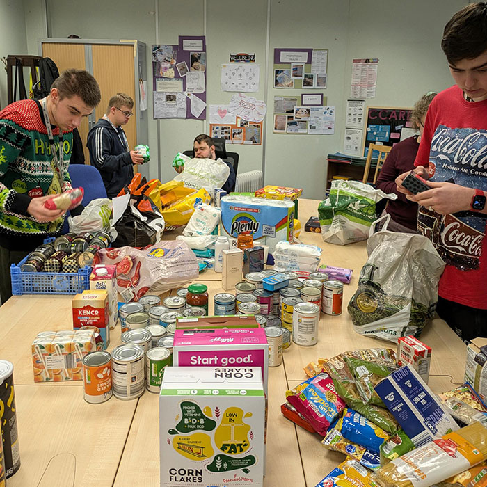 The student council are pictured sorting all of the long-life food into categories on a table.