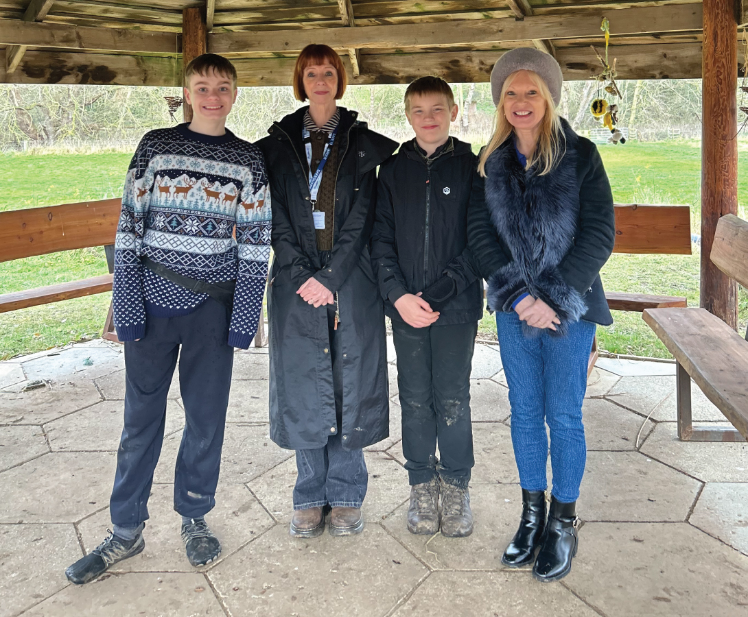 Executive principal of Clervaux Garden School, Allison Rice, is standing smiling with two students at an Hargreaves Land employee shelter.