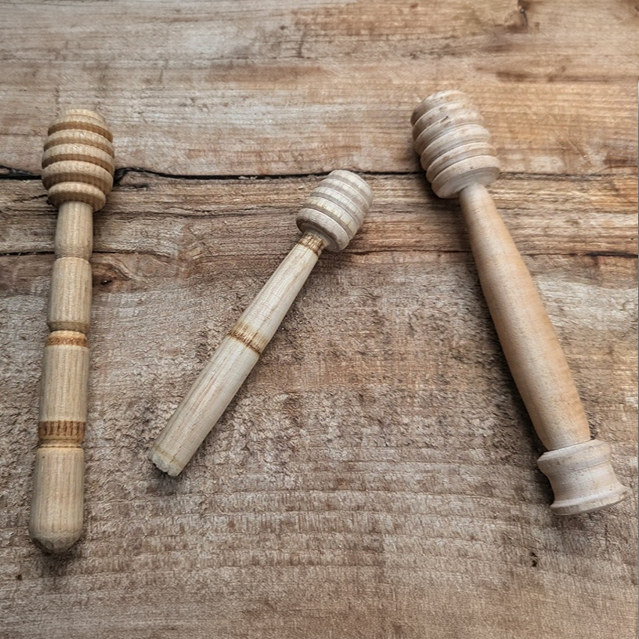 Three wooden honey dippers created by K, with a Green Wood Working finish, placed on a table.